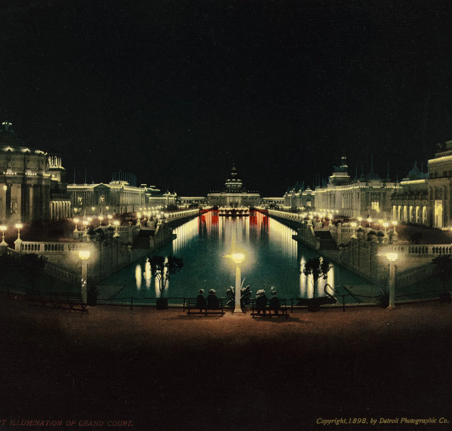Illuminated exposition buildings reflected in the Grand Court canal in Omaha at night